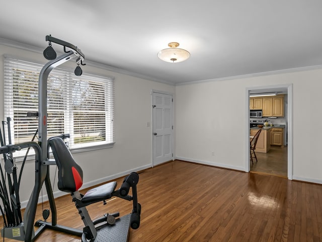 exercise area featuring baseboards, ornamental molding, and wood finished floors