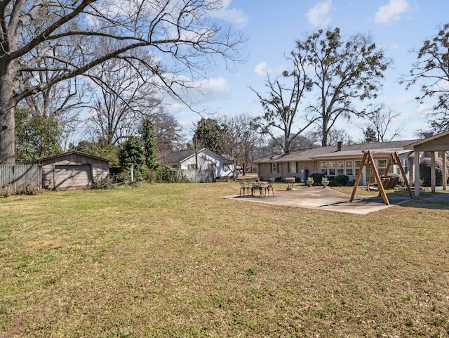 view of yard featuring a patio area, fence, and an outbuilding