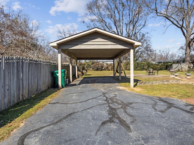 view of parking / parking lot with a carport, fence, and driveway