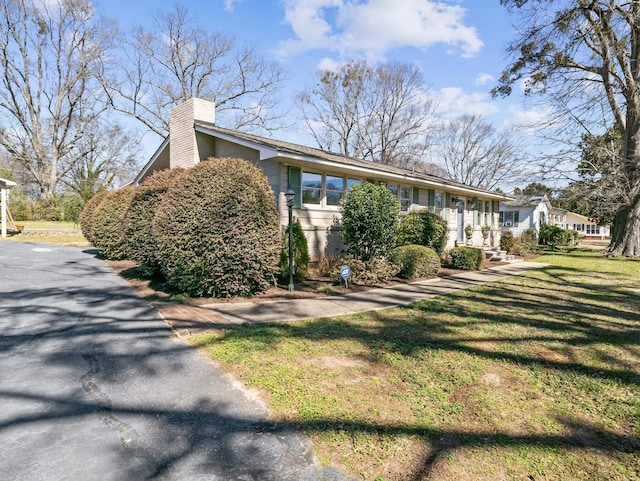 view of front of house with a chimney and a front lawn