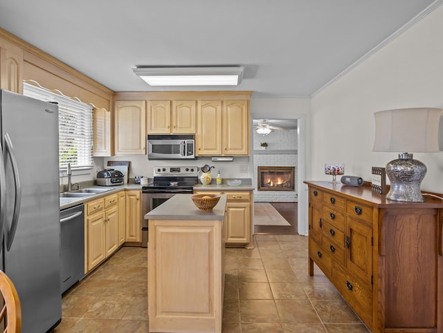 kitchen featuring appliances with stainless steel finishes, ornamental molding, light brown cabinets, a sink, and a kitchen island