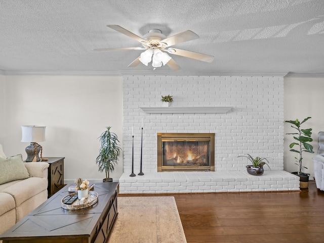 living room with crown molding, a fireplace, ceiling fan, and wood finished floors