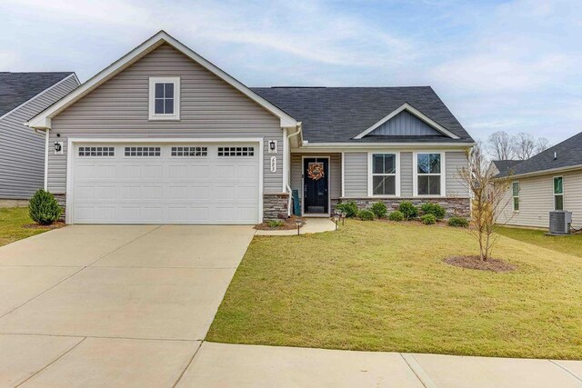 view of front of property with concrete driveway, stone siding, an attached garage, central air condition unit, and a front yard