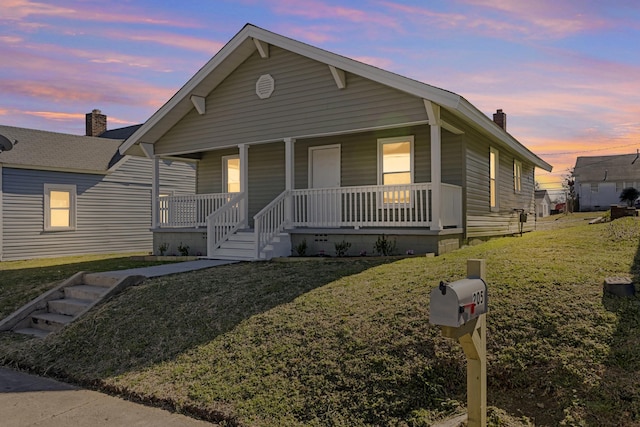 view of front facade featuring a porch, a front lawn, and a chimney