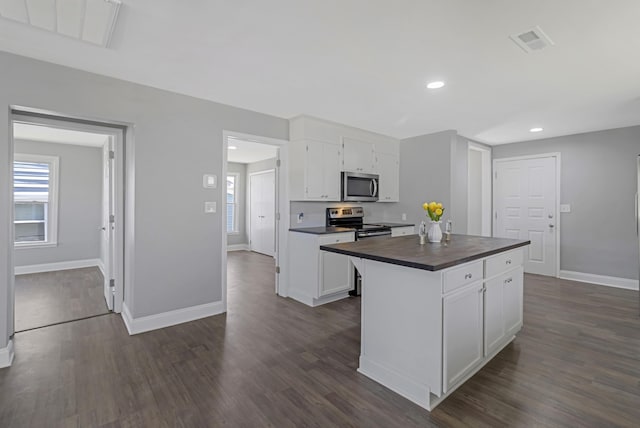 kitchen featuring appliances with stainless steel finishes, visible vents, dark wood finished floors, and white cabinetry