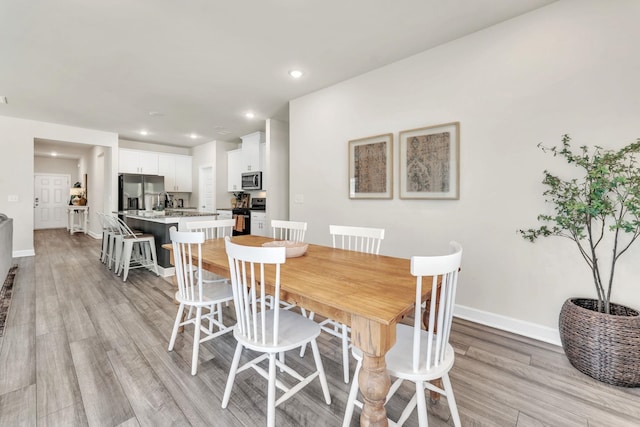 dining room with light wood-style floors, baseboards, and recessed lighting