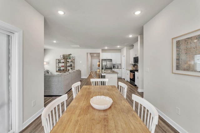 dining space featuring baseboards, wood finished floors, and recessed lighting