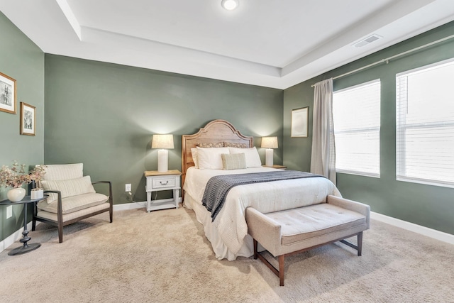 bedroom with a tray ceiling, carpet flooring, visible vents, and baseboards