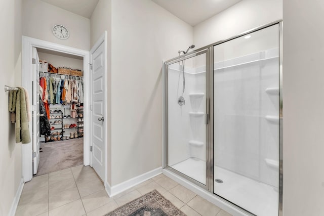 full bathroom featuring a stall shower, a spacious closet, baseboards, and tile patterned floors