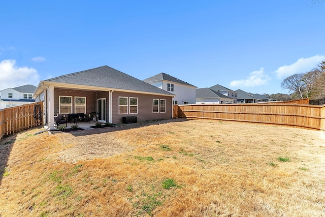 rear view of house featuring a patio area, a yard, and a fenced backyard