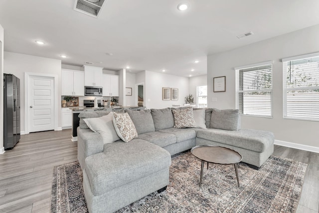 living area featuring a wealth of natural light, light wood-style flooring, and visible vents