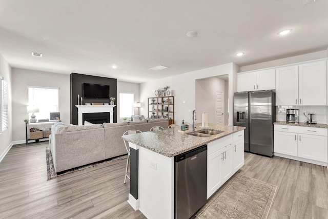 kitchen with visible vents, appliances with stainless steel finishes, light wood-style floors, a sink, and an island with sink