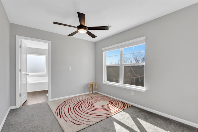 carpeted empty room featuring ceiling fan and baseboards