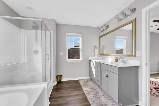 bathroom with a stall shower, a sink, baseboards, and wood finished floors