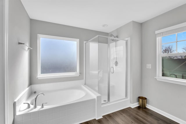 full bathroom with a garden tub, a shower stall, baseboards, and wood finished floors