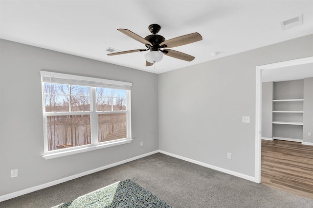 unfurnished bedroom with a ceiling fan, carpet, visible vents, and baseboards