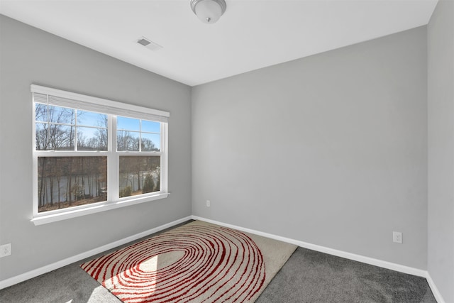 spare room with carpet floors, visible vents, and baseboards