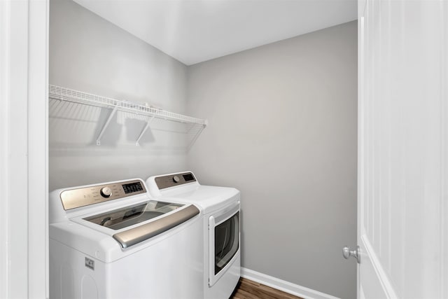 laundry room with dark wood-style flooring, laundry area, baseboards, and washing machine and clothes dryer