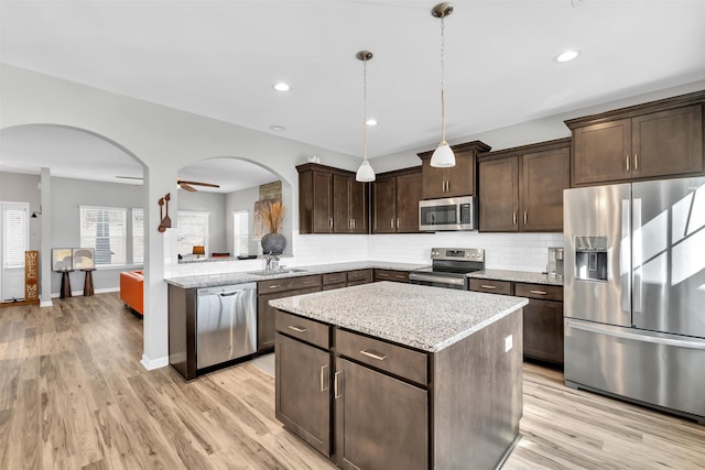 kitchen with stainless steel appliances, a center island, dark brown cabinetry, and tasteful backsplash