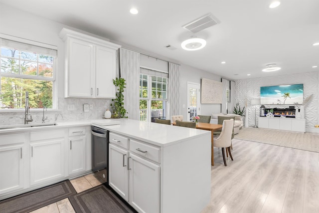 kitchen with recessed lighting, open floor plan, a sink, and a glass covered fireplace