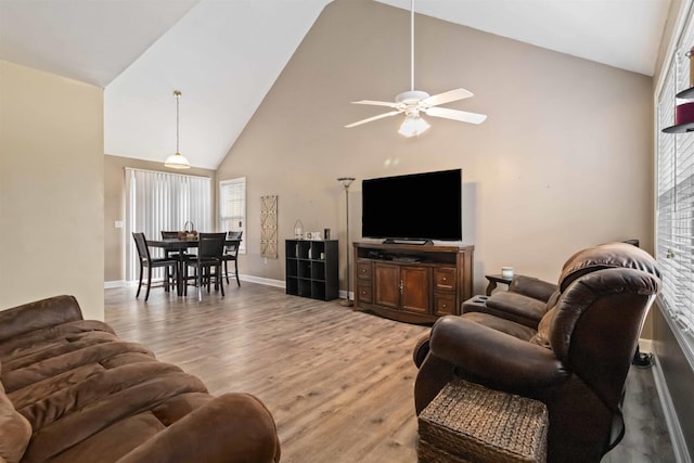 living area featuring high vaulted ceiling, light wood-type flooring, baseboards, and a ceiling fan