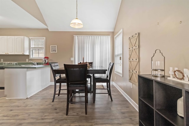 dining room featuring lofted ceiling, wood finished floors, and baseboards