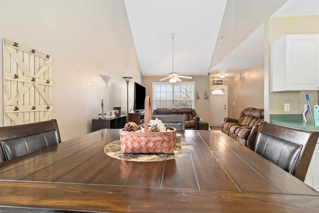 dining area featuring ceiling fan, high vaulted ceiling, and a barn door