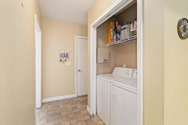 laundry area with stone finish floor, laundry area, washing machine and dryer, and baseboards