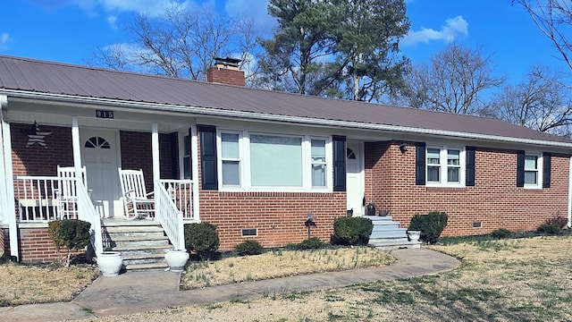 view of front facade with a chimney, metal roof, crawl space, a porch, and brick siding