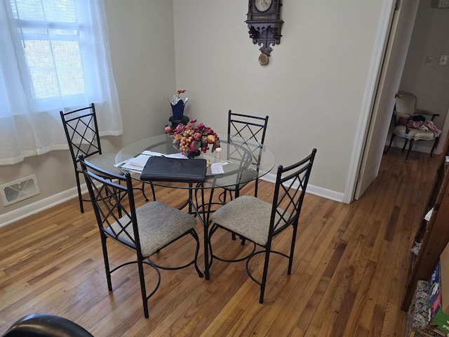 dining space featuring wood-type flooring, visible vents, and baseboards