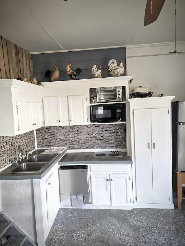 kitchen with appliances with stainless steel finishes, white cabinets, a sink, and backsplash