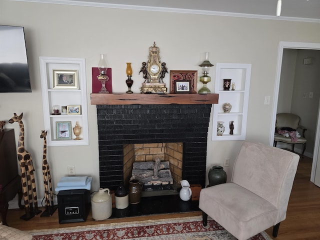 living room featuring built in features, a fireplace, crown molding, and wood finished floors