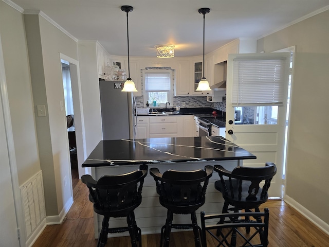 kitchen featuring visible vents, dark countertops, appliances with stainless steel finishes, white cabinetry, and backsplash