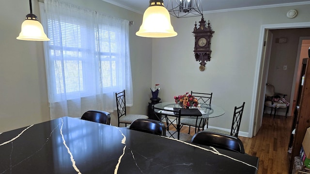 dining area with baseboards, wood finished floors, and crown molding