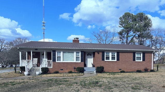 view of front of home featuring crawl space, brick siding, metal roof, and a chimney