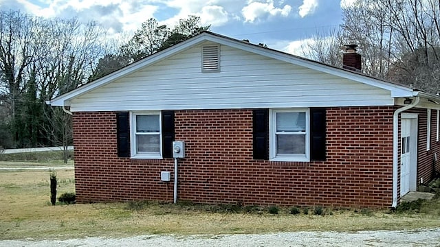 view of side of property featuring brick siding and a chimney