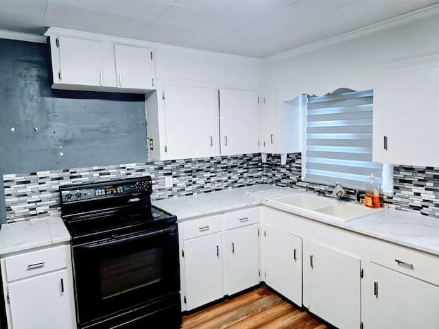 kitchen with white cabinets, backsplash, black electric range oven, light wood-type flooring, and a sink