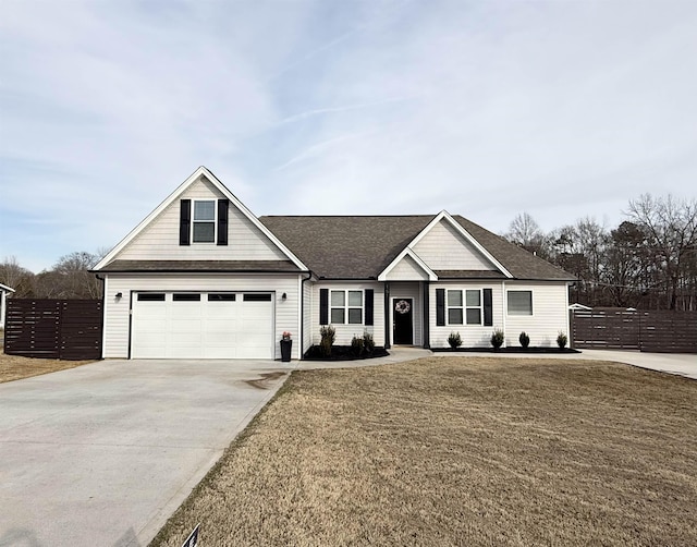 view of front of home featuring a garage, concrete driveway, roof with shingles, fence, and a front yard