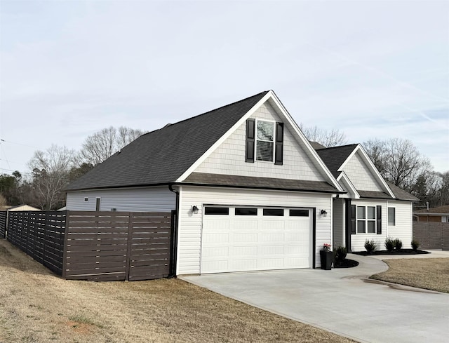 view of front facade featuring a garage, driveway, a shingled roof, and fence