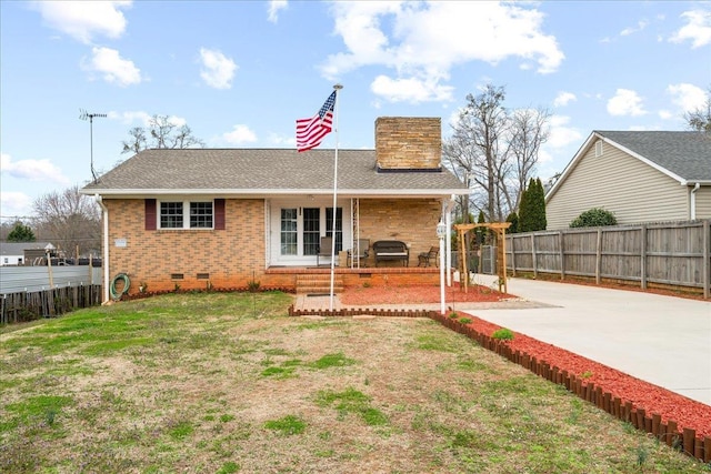 rear view of property with brick siding, fence, a yard, crawl space, and a chimney