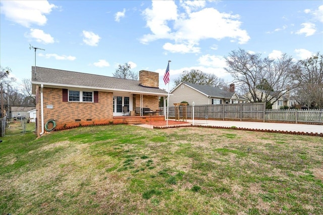 rear view of house featuring a patio, a chimney, crawl space, a yard, and brick siding