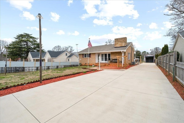 view of front facade with a garage, brick siding, an outdoor structure, fence, and a chimney