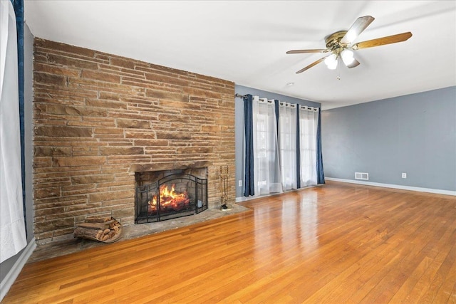 unfurnished living room featuring a fireplace, wood finished floors, visible vents, and baseboards