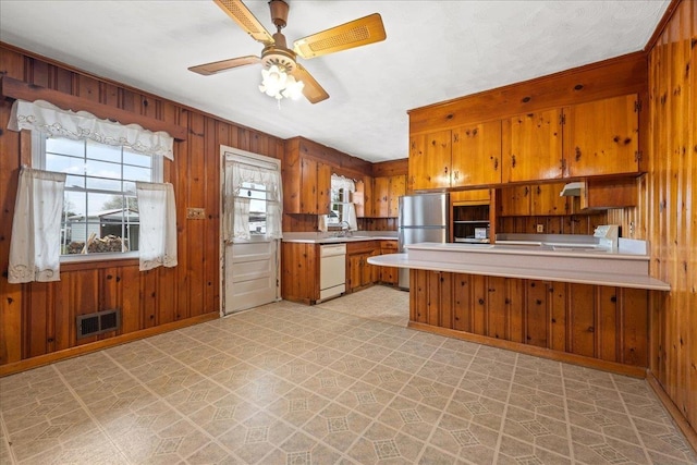 kitchen with white dishwasher, visible vents, freestanding refrigerator, light floors, and brown cabinetry