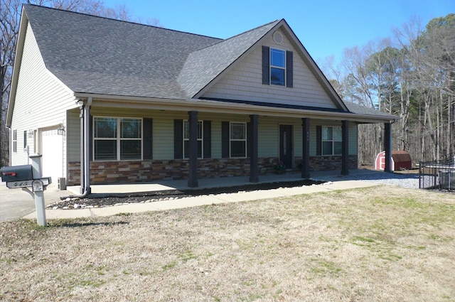 view of front of house with stone siding, a porch, roof with shingles, an attached garage, and a front lawn