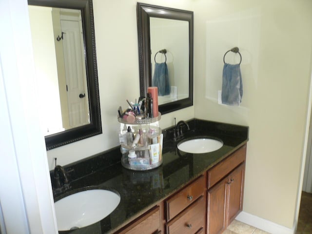 bathroom with a sink, baseboards, and double vanity