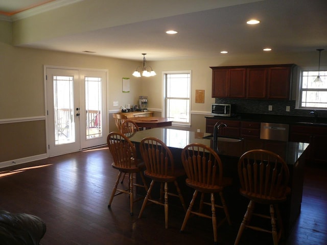 kitchen featuring dark wood-style floors, appliances with stainless steel finishes, a sink, french doors, and backsplash