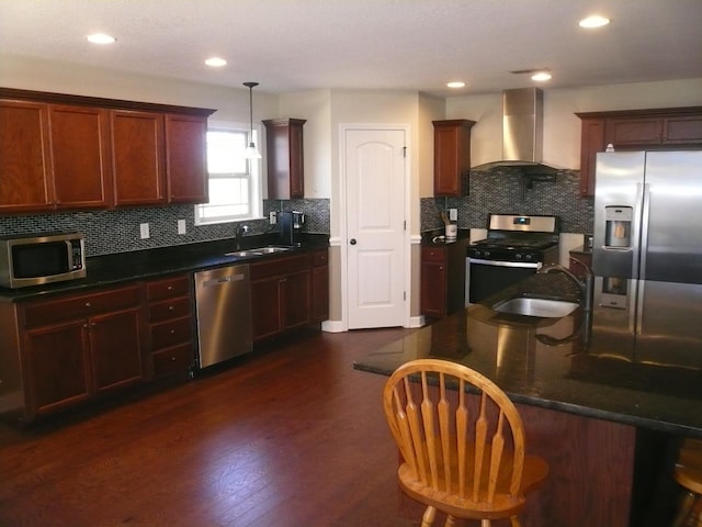 kitchen with stainless steel appliances, pendant lighting, a sink, and wall chimney range hood