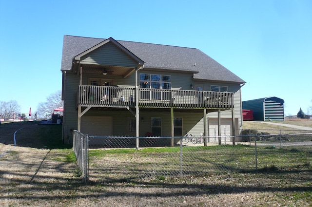 rear view of property with a garage, fence private yard, ceiling fan, and a yard