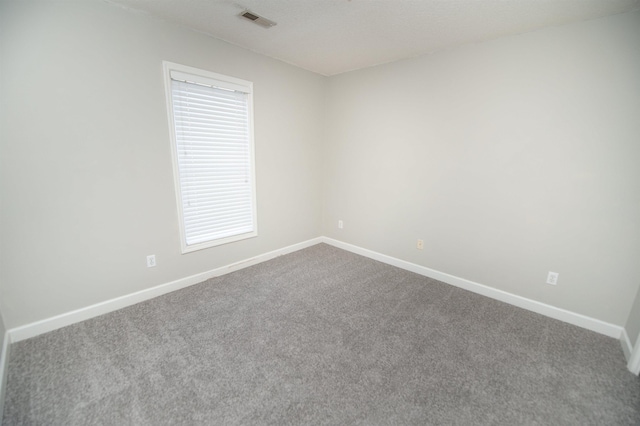 unfurnished room featuring dark colored carpet, visible vents, and baseboards